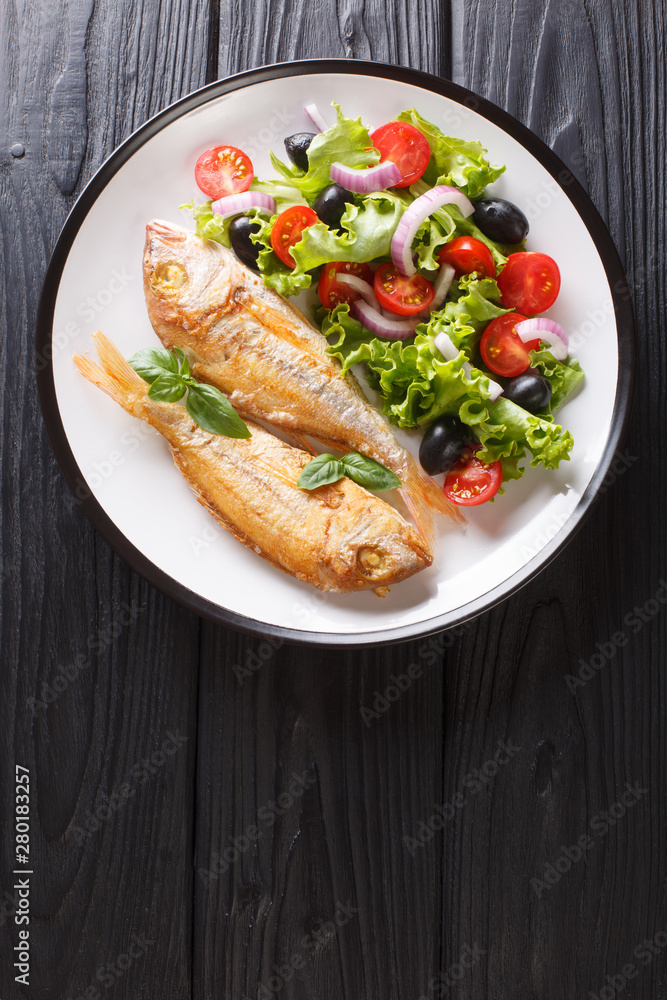 fried pink dorado served with lemon and fresh vegetables close-up on a plate. Vertical top view fried pink dorado served with lemon and fresh vegetables close-up on a plate. Vertical top view