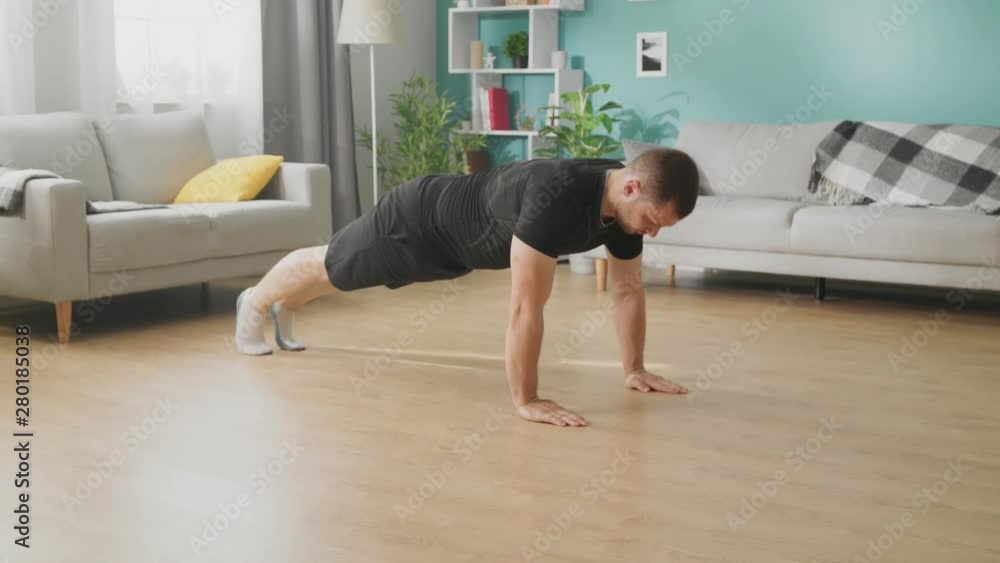 A young man does push-ups in the afternoon in his living room