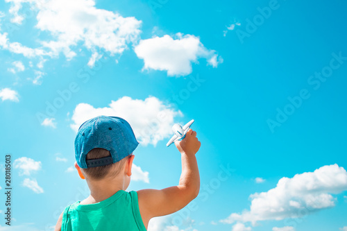 Little boy hold toy plane on a background of blue sky with white clouds © Iryna Burmii