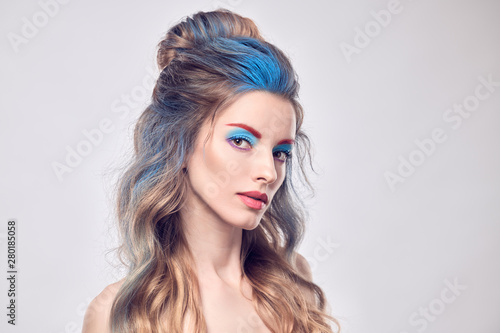 High Fashion. Beautiful woman with art paint makeup  creative Dyed hairstyle. Gorgeous blonde girl with styling wavy hair  healthy skin. Young model girl  fashionable make up. Creative Beauty portrait