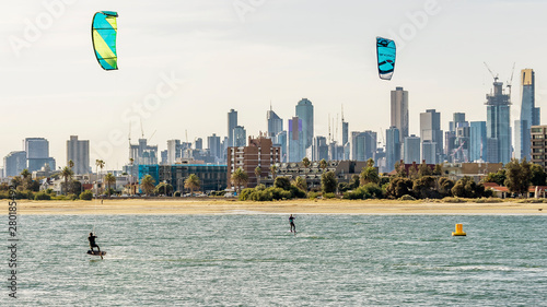 Pair of kitesurfers trains in Port Phillip Bay, with the skyline of Melbourne, Australia in the background photo