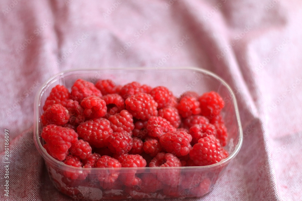 Fresh raspberries in a container. Selective focus, pink background. Fresh raspberries in a container. Selective focus, pink background.