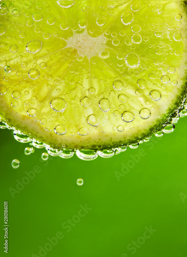 Close up of water with lime slice and bubbles. Macro shot