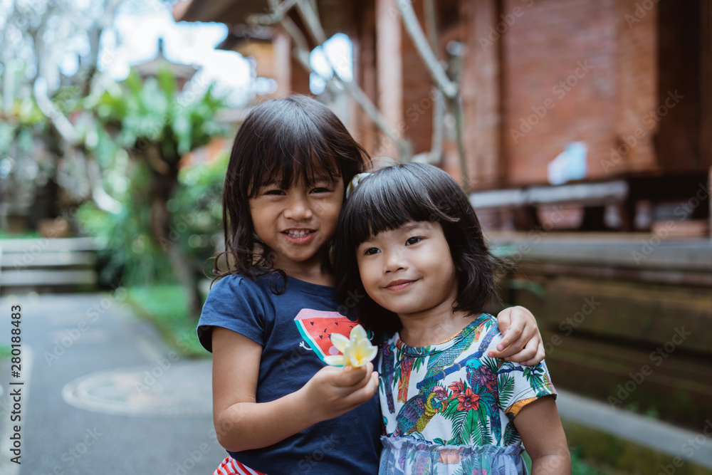 happiness two pretty girl standing in front of the house, smile and hugging each other happiness two pretty girl standing in front of the house, smile and hugging each other