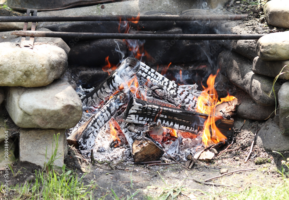 Burnt out logs in homemade camp fire created mainly oval stone. Fire is ready for fry meat. Cinders. Outdoor casual view. Garden relax Burnt out logs in homemade camp fire created mainly oval stone. Fire is ready for fry meat. Cinders. Outdoor casual view. Garden relax