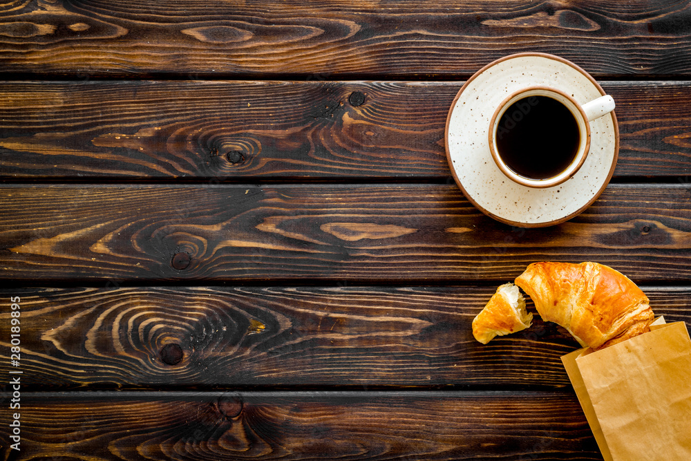 Fototapeta Fresh pastry with croissant in paper bag and cup of coffee on wooden background top view mockup