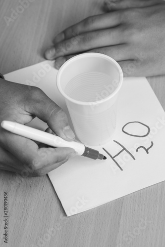 teenager writes marker chemical formulas on a white sheet with a glass of water