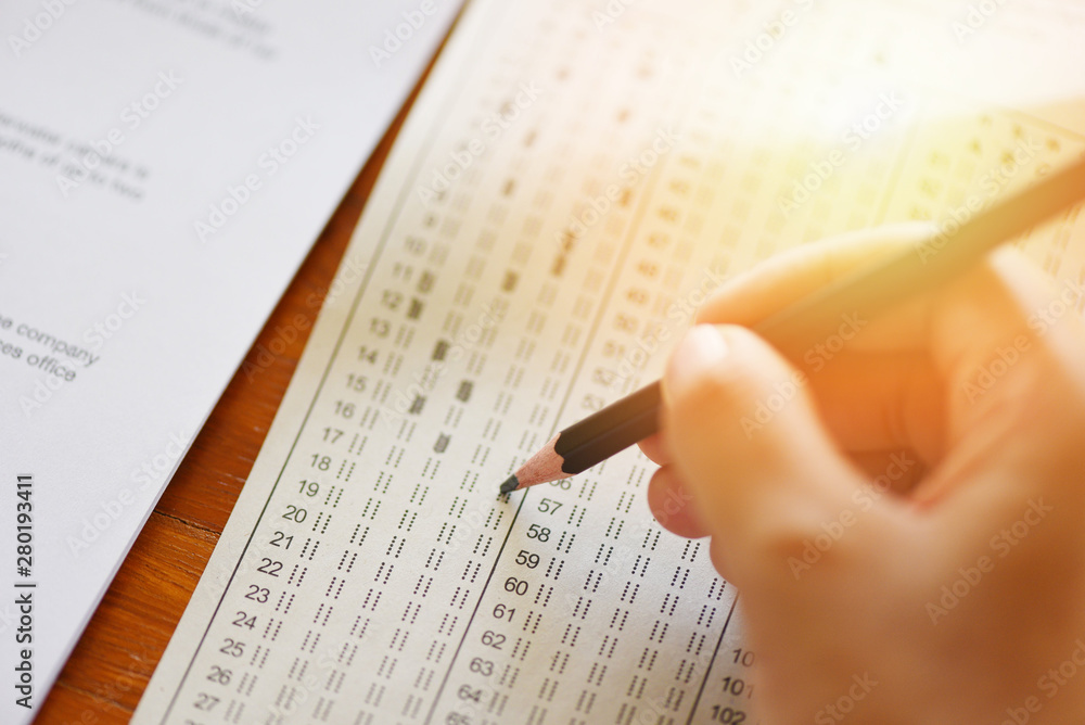 Obraz premium take the exam final high school hand student holding pencil writing on paper answer sheet - education college in class taking notes sitting learning writing selected choice in examination room