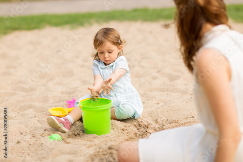 childhood, leisure and people concept - little baby girl plays with toys in sandbox