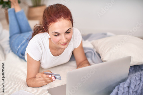 the student is happy to communicate with friends via the Internet. home schooling, work and study, new knowledge.happy teen on bed with computer. girl student lying on the bed smiling.