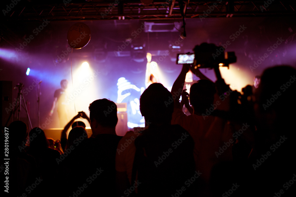 Cheering crowd in concert show having fun and applause in front of stage lights