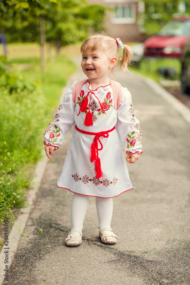 Baby girl in Ukrainian embroidery walking across field with daisies and carrying Ukrainian flag. child waving flying flag of yellow-blue. Happy child on Independence Day Ukraine and Flag Day Baby girl in Ukrainian embroidery walking across field with daisies and carrying Ukrainian flag. child waving flying flag of yellow-blue. Happy child on Independence Day Ukraine and Flag Day