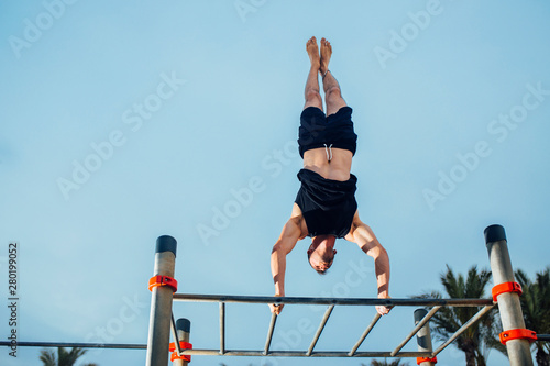 fitness, sport, training, calisthenics and lifestyle concept - man doing a handstand exercise in calisthenics park