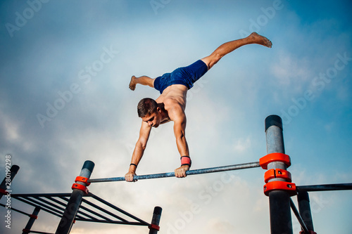 fitness, sport, training, calisthenics and lifestyle concept - young man exercising handstand on bar outdoors © dark_saiyaman