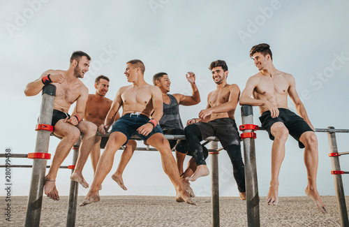 group of sports friends sittigroup of sports friends having a fun time on the street training barsng on the street training bars looking at camera