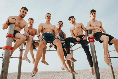 group of sports friends sitting on the street training bars looking at camera