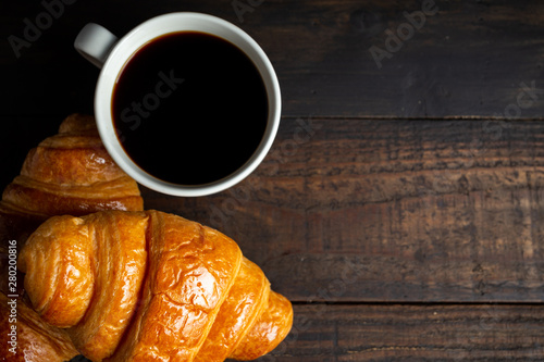croissants and coffee on old wooden table.