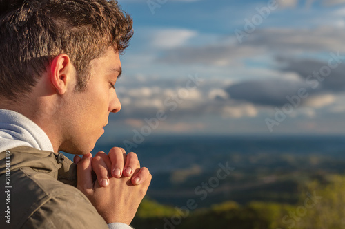 Christian worship and praise. A young man is praying and worshiping in the evening.