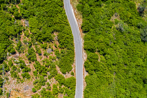 Aerial view of road in high mountains among green trees.