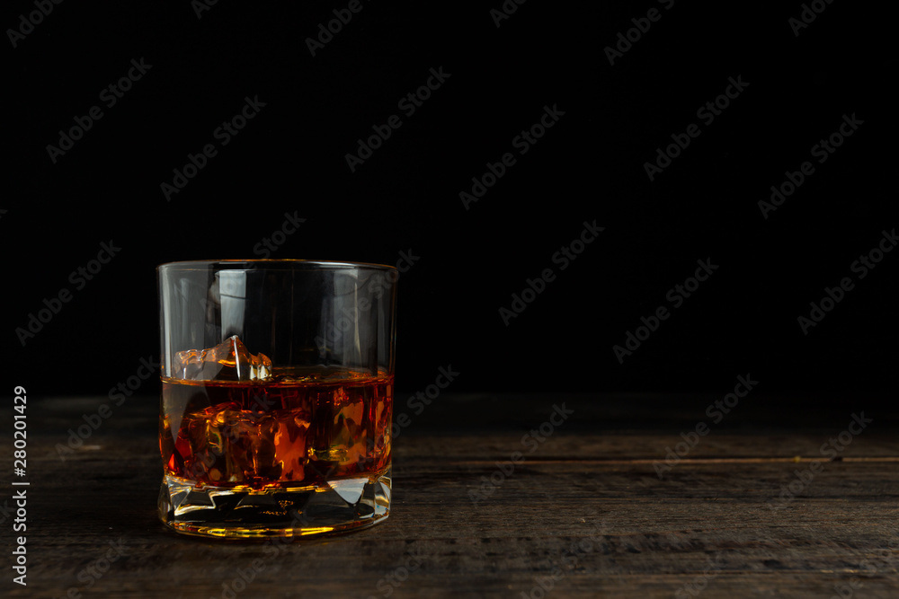 glasses of whiskey with ice cubes on wooden.