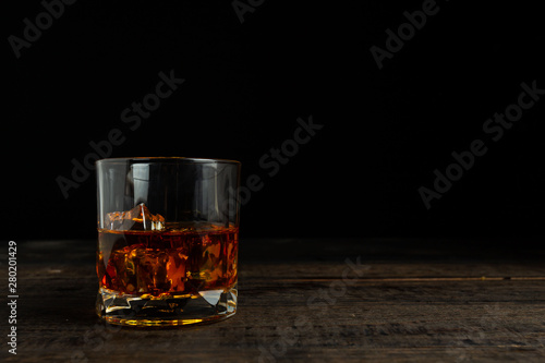 glasses of whiskey with ice cubes on wooden.