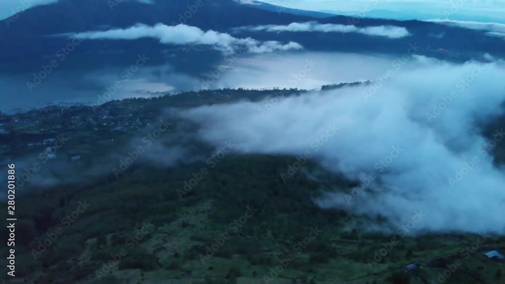 Clouds on the Bali landscape at sunrise seen from a drone high overhead. Beautiful morning scene from drone flying in reverse over the terrain near Mount Batur. Clouds on the Bali landscape at sunrise seen from a drone high overhead. Beautiful morning scene from drone flying in reverse over the terrain near Mount Batur.