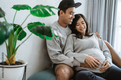 Billede på lærred happiness couples feel the pregnancy, holding the wife's pregnant stomach, sitti