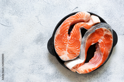 Fresh, raw salmon steak with spices on a stone background. View from above. photo