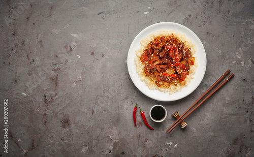 Sweet and Sour fried pork chunks with vegetables and rice on grey stone background. Top view with copy space photo