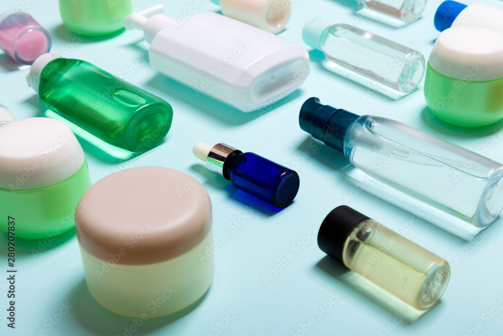 Top view of cosmetic products in different jars and bottles on blue background. Close-up of containers with copy space Top view of cosmetic products in different jars and bottles on blue background. Close-up of containers with copy space