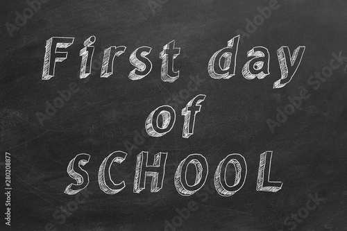 Hand drawing text "First Day of School" on blackboard.