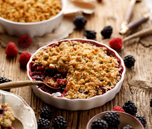 Mixed berry (blackberry, raspberry) crumble in a baking dish on a wooden table, close-up