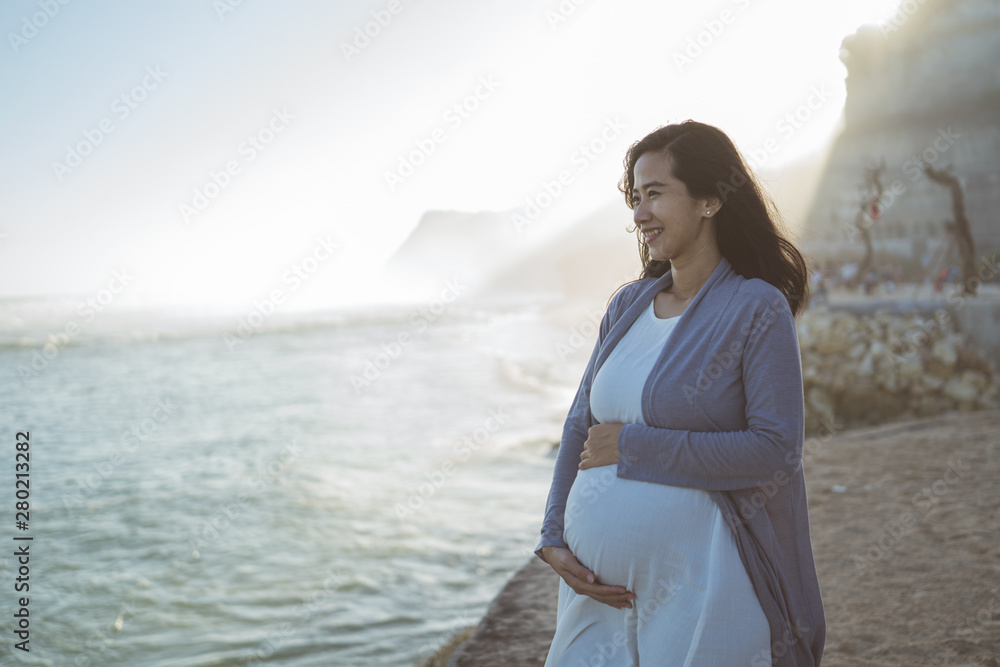 beautiful pregnant woman standing on the beach when sunrise in the morning beautiful pregnant woman standing on the beach when sunrise in the morning