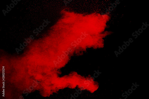 Red color powder explosion on black background.Freeze motion of red dust particles splashing.