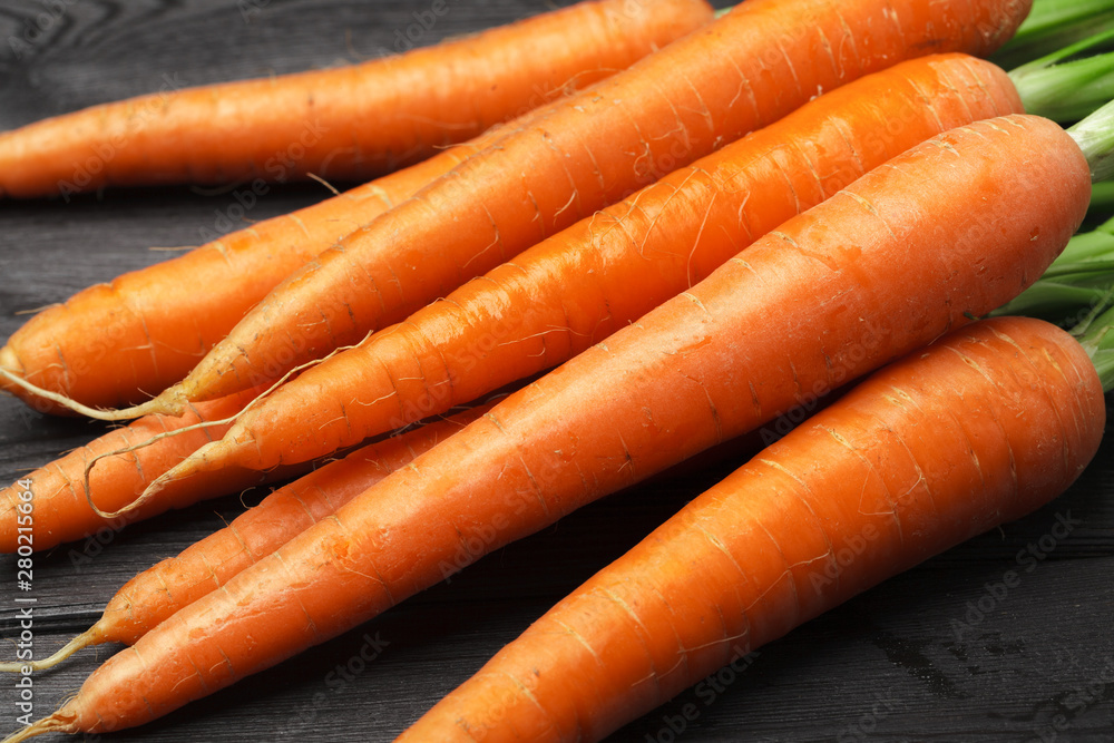 Bunch of fresh carrots with green leaves on wooden table Bunch of fresh carrots with green leaves on wooden table