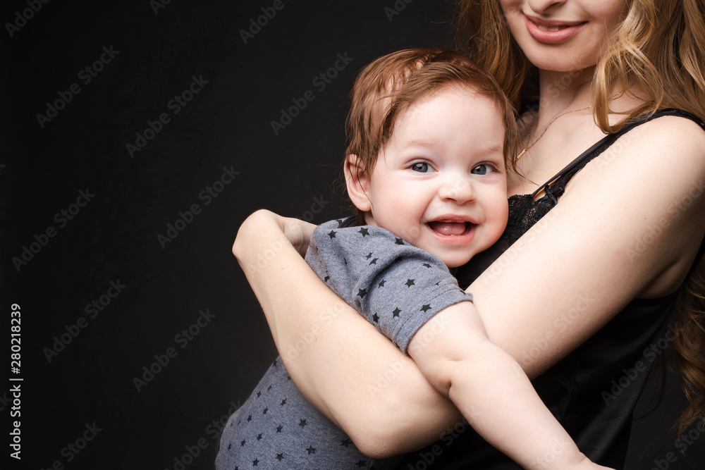 Close-up of cute baby boy smiling at camera while mother is holding him on her loving arms. Close-up of cute baby boy smiling at camera while mother is holding him on her loving arms.