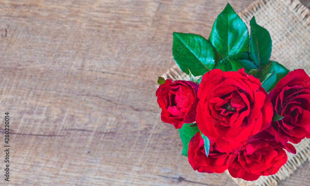 Flat lay of Beautiful rose red on sack and wooden table with , copy empty space.