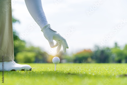Professional Golf Player hand putting golf ball on tee in golf course
