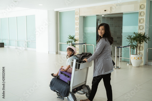 portrait mother and his daughter walking with trolley when waiting flight departure