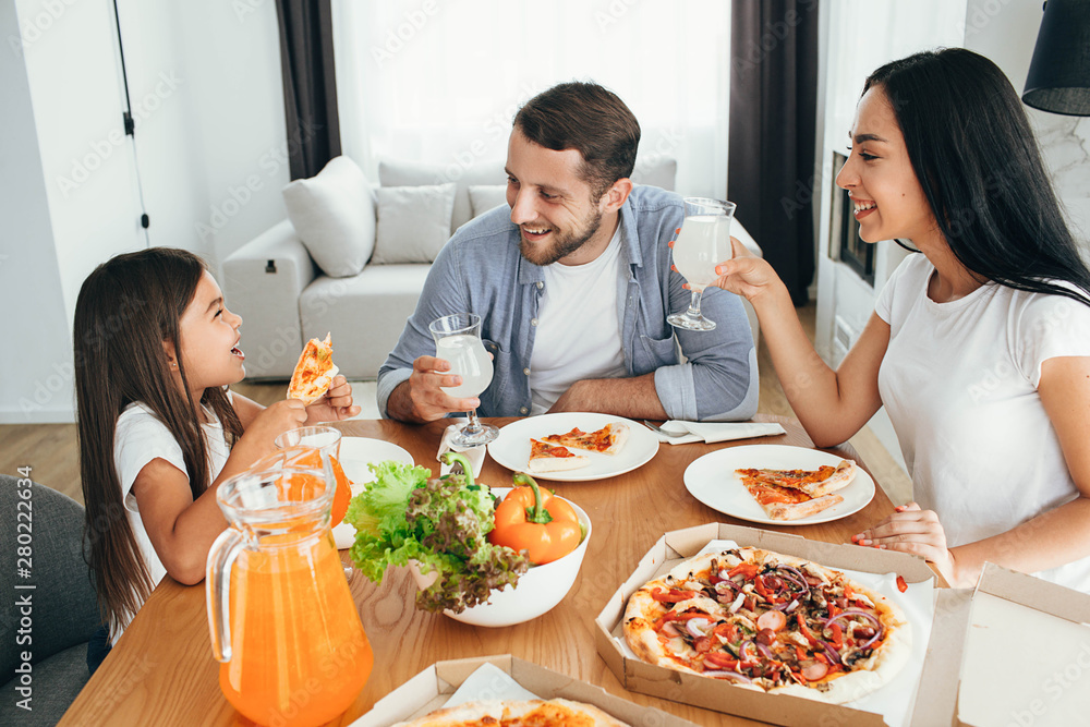 happy multi ethnic family, mother, father and daughter during dinner.Eating delicious pizza with family happy multi ethnic family, mother, father and daughter during dinner.Eating delicious pizza with family