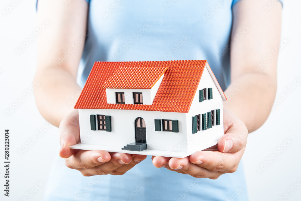 Female hands holding up a small house model Female hands holding up a small house model