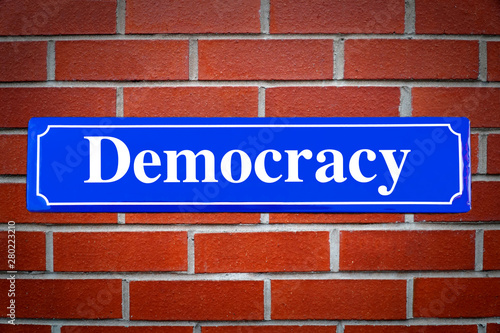 Democracy street sign on brick wall photo