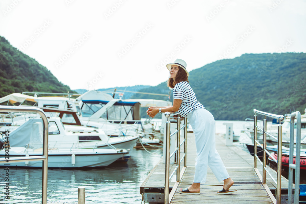 smiling woman in white standing in dock enjoying the view boats on background smiling woman in white standing in dock enjoying the view boats on background