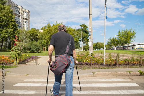 Disabled person on crutches crosses the carriageway at a crosswalk