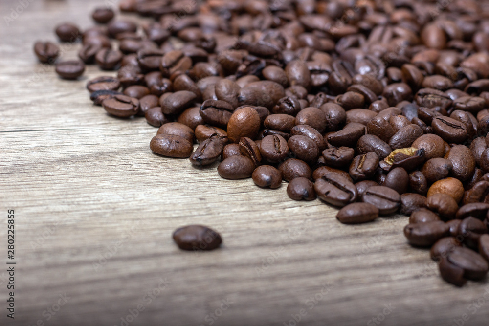 Roasted coffee beans, on a wooden surface. Roasted coffee beans, on a wooden surface.