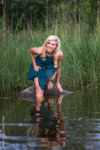 Beautiful blonde woman in the lake in blue dress