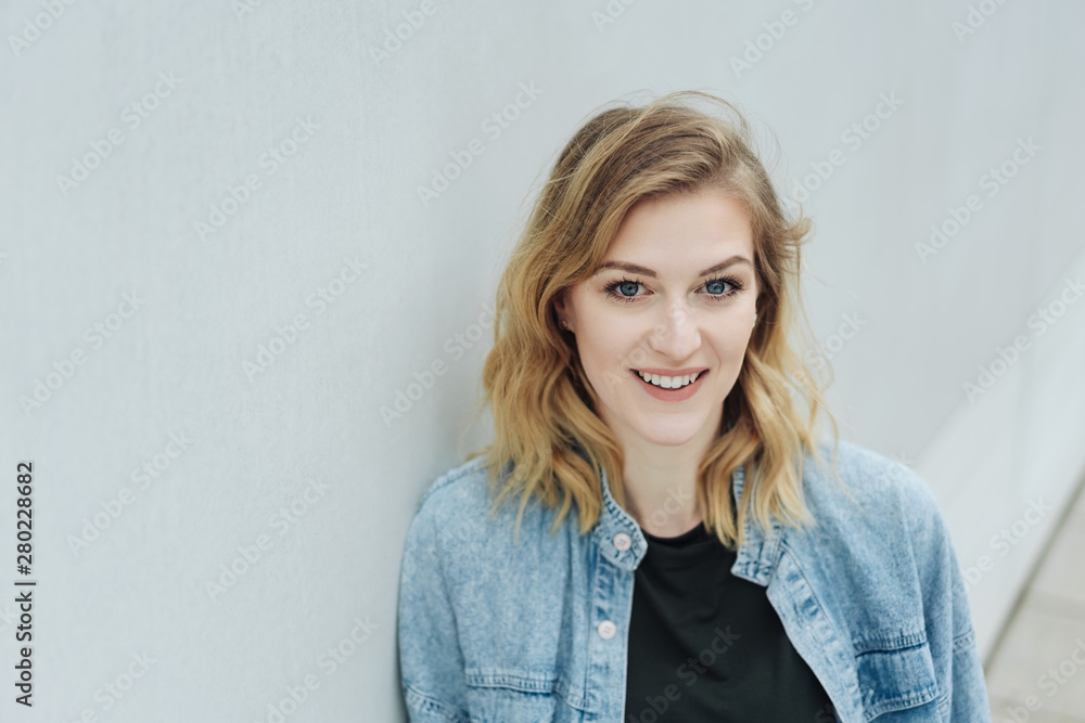 Young blond woman relaxing leaning on a wall Young blond woman relaxing leaning on a wall
