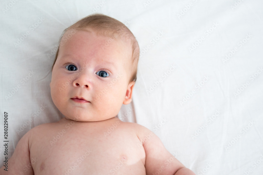 The baby a surprised expression. Newborn lying on a white background .Top view The baby a surprised expression. Newborn lying on a white background .Top view