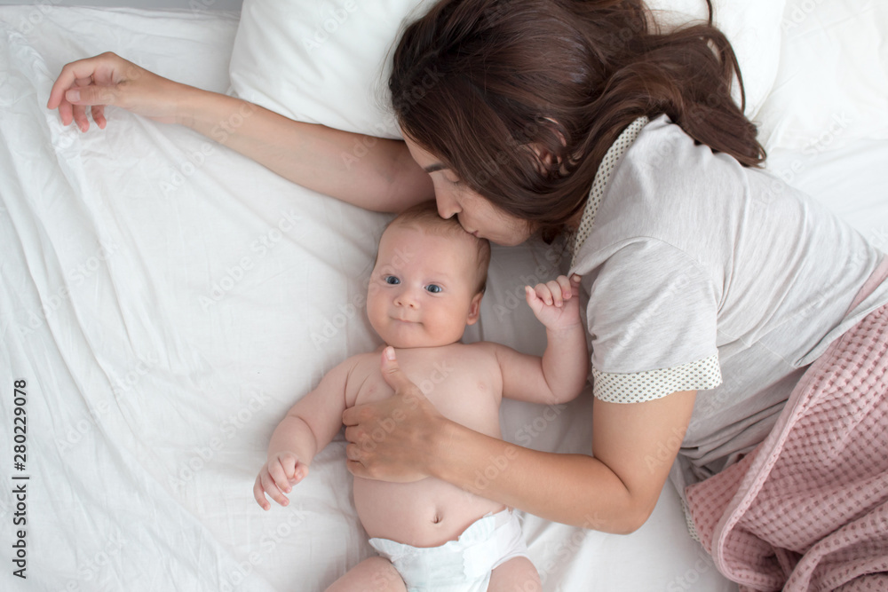 Baby and mom. A brunette woman lies with a blond child. Top view Baby and mom. A brunette woman lies with a blond child. Top view