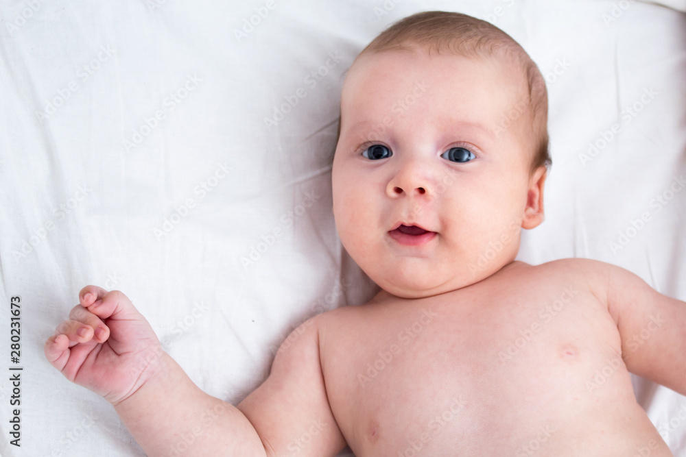 The baby smiles. Newborn lying on a white background .Top view The baby smiles. Newborn lying on a white background .Top view